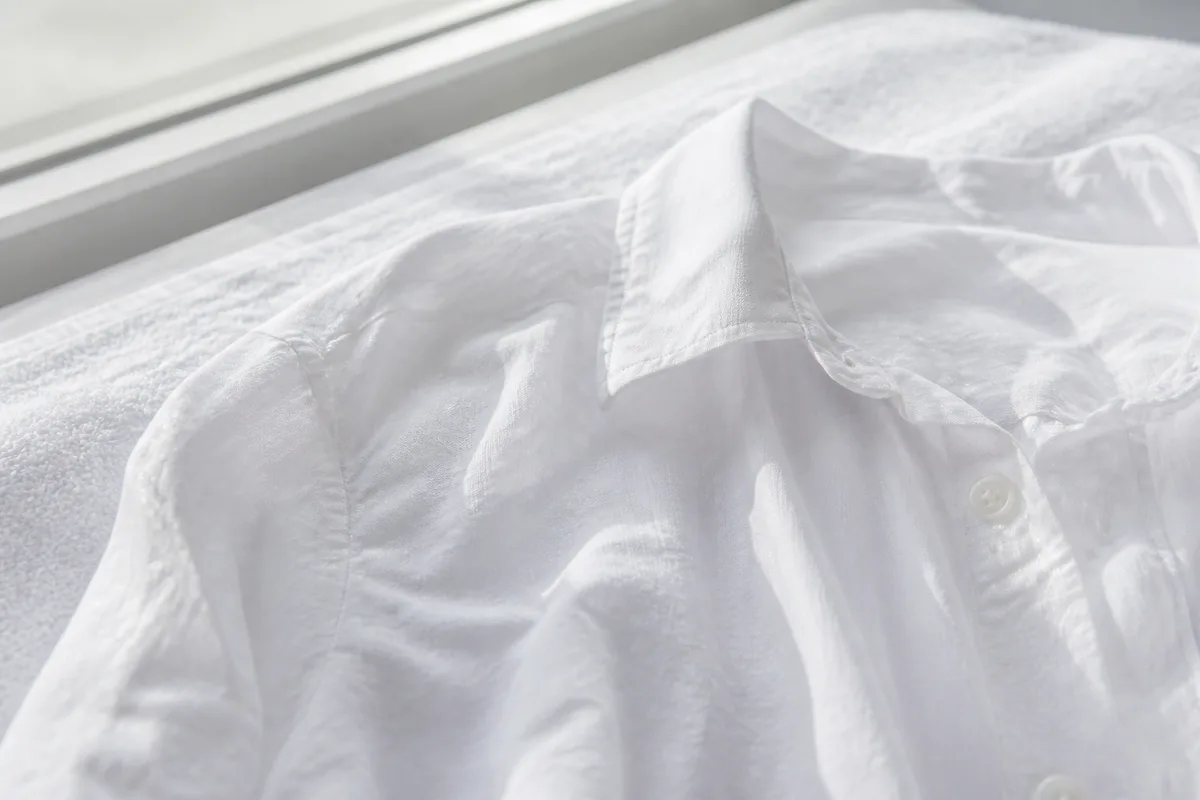 Detail d une chemise en coton clair etendue a plat pour secher pres d une fenetre